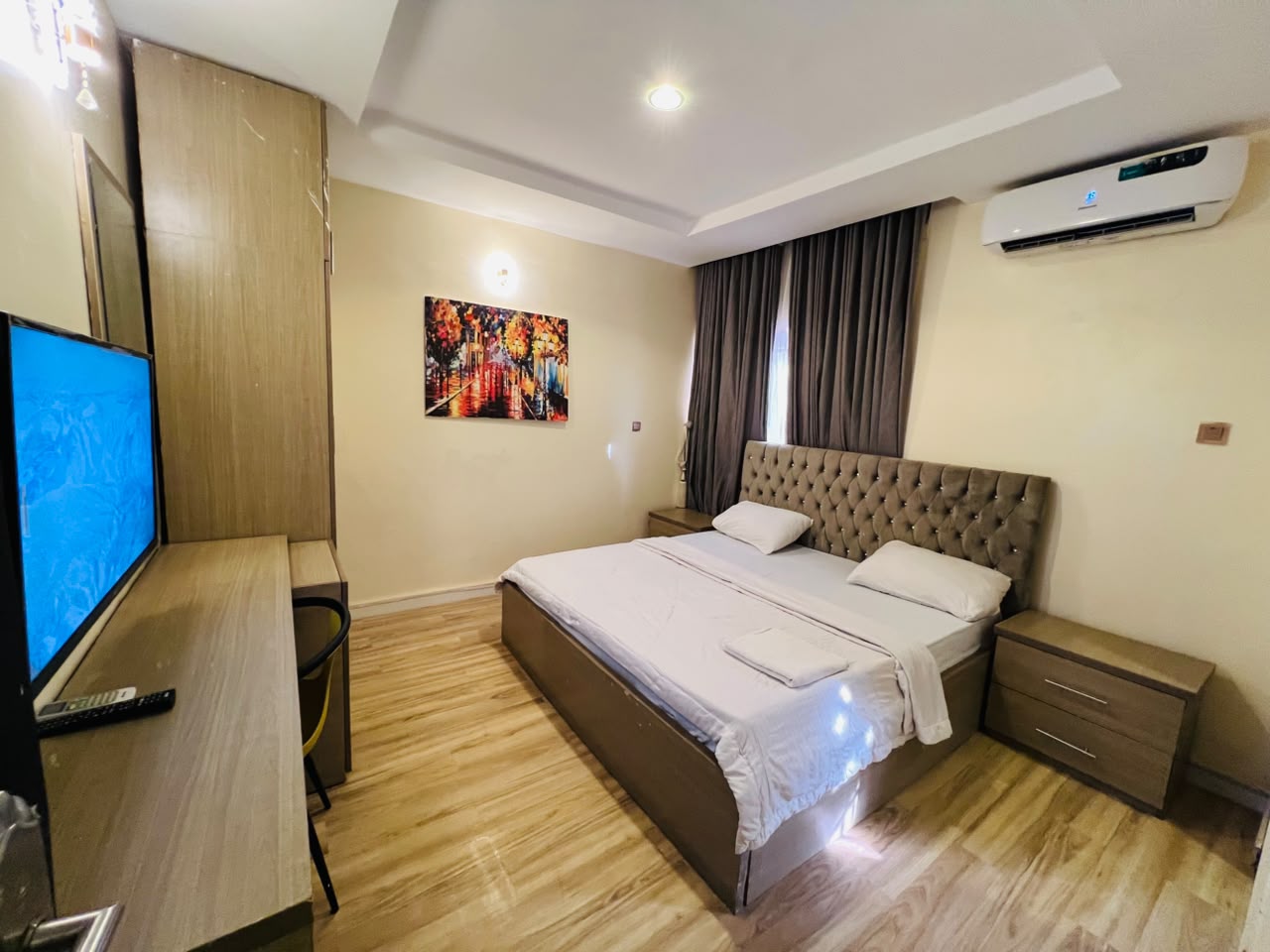 Wide view of the Ambassador Retreat private room, with a double bed, wall-mounted television, desk, fitted wardrobe and air conditioning
