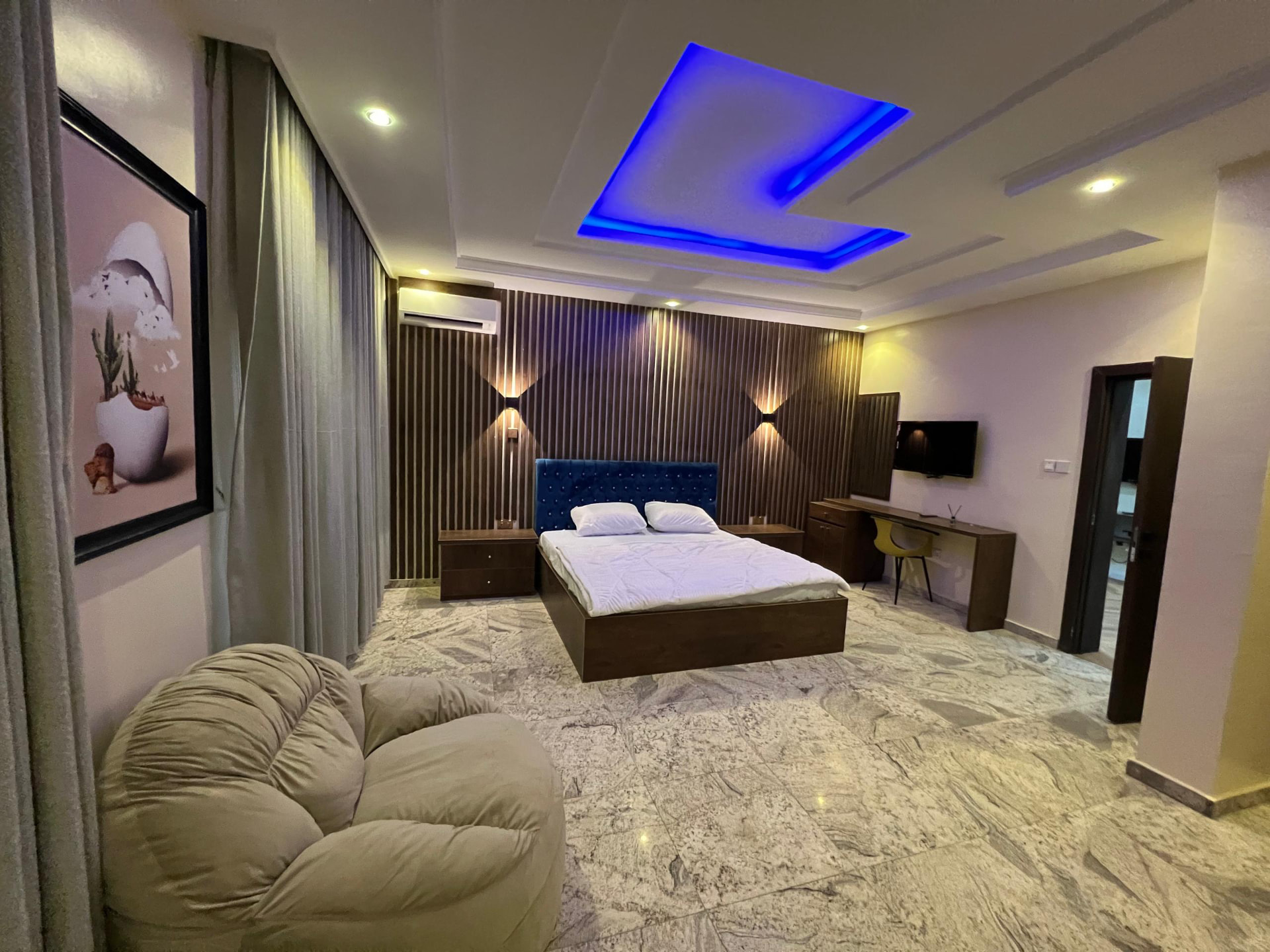 Presidential Suite, Apo Legislative Quarters — wide view of the furnished private suite with double bed, accent wall, work desk, television and seating chair